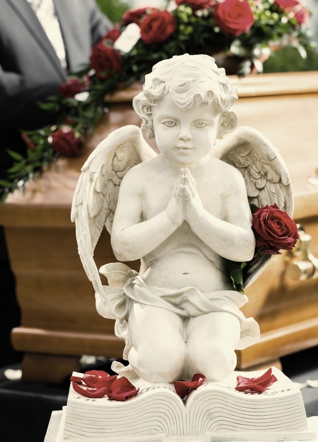 Białe kwiaty i figura anioła w dekoracji pogrzebowej